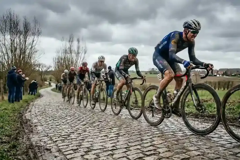 Cyclistes professionnels sur les pavés légendaires d'une classique cycliste dans la poussière et la boue